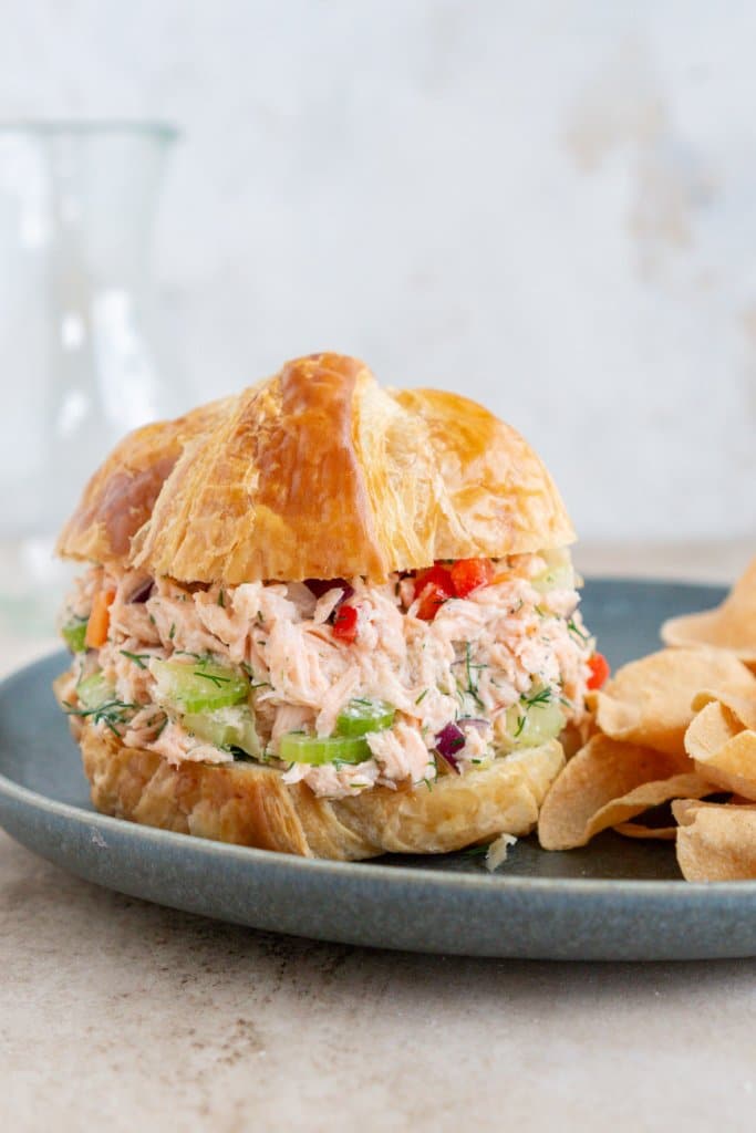 a salmon salad sandwich on a grey plate with chips