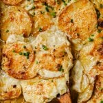 sheet pan scalloped potatoes with a wooden serving spoon