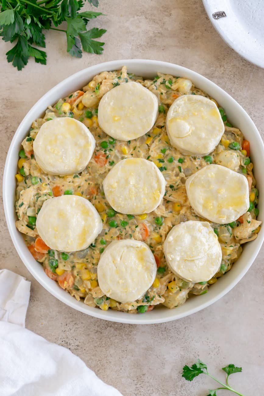 Uncooked filling in a baking dish with unbaked biscuits on top.