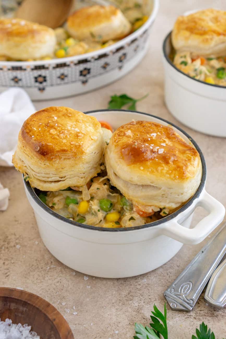 Turkey pot pie with two biscuits in a white handled bowl.