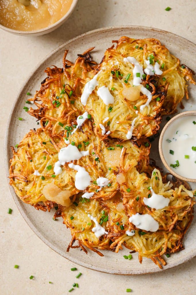 air fryer latkes on a plate with sour cream drizzled on top