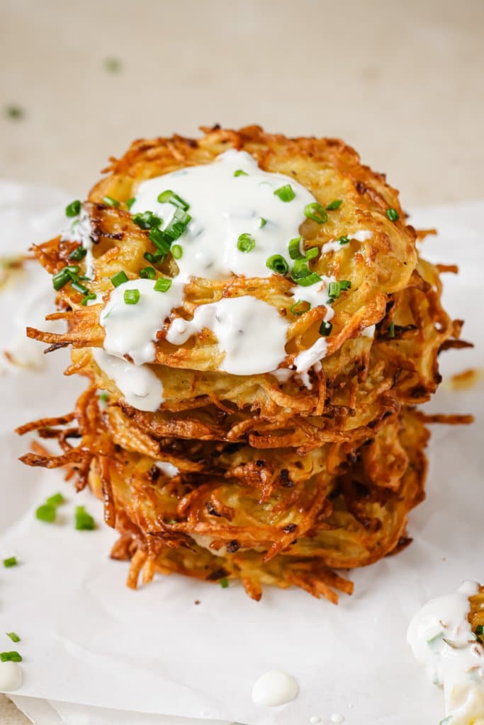 air fryer latkes stacked on top of each other with sour cream on top