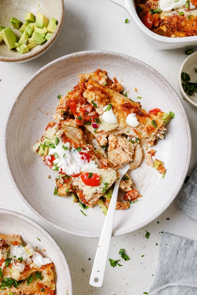 a white plate with turkey enchiladas and a fork