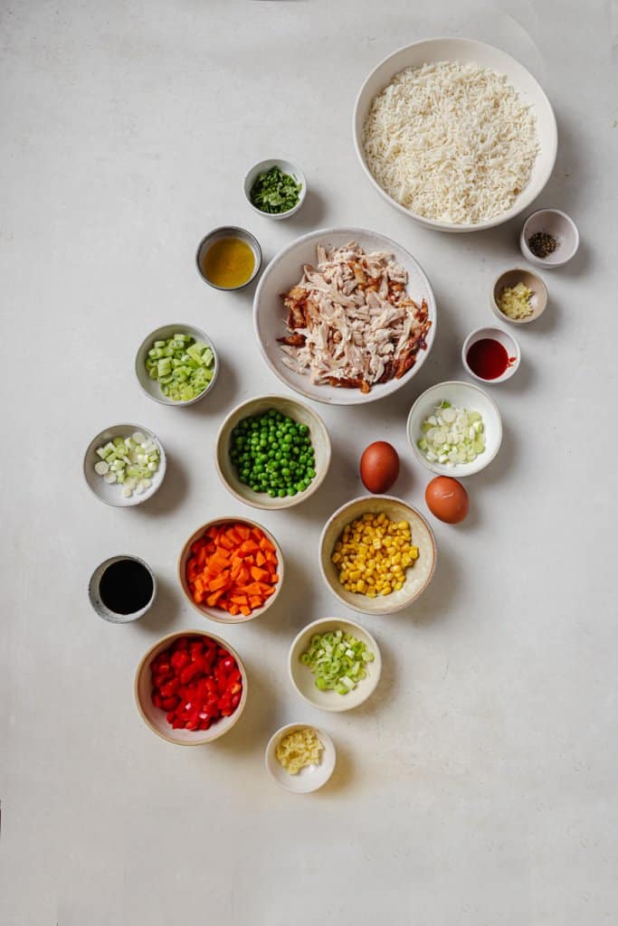 leftover turkey, red pepper, rice, onion, corn, green onion, carrots, and spices in small ingredient bowls