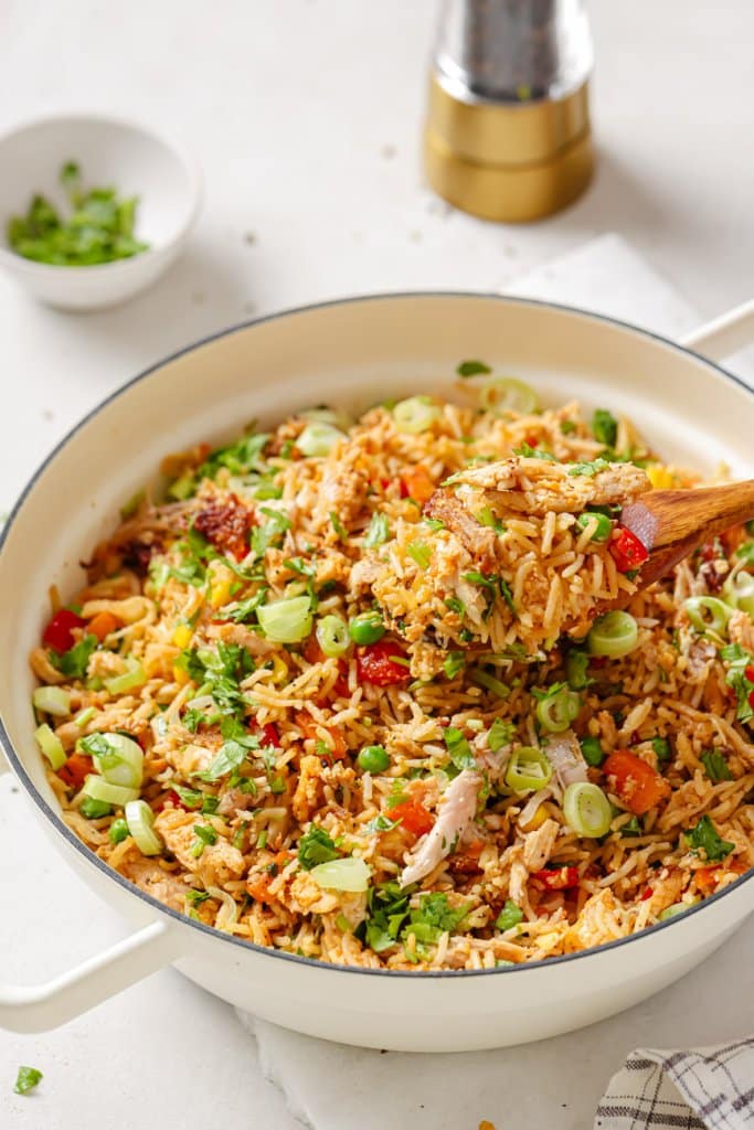 a wooden spoon serving leftover turkey fried rice from a pot
