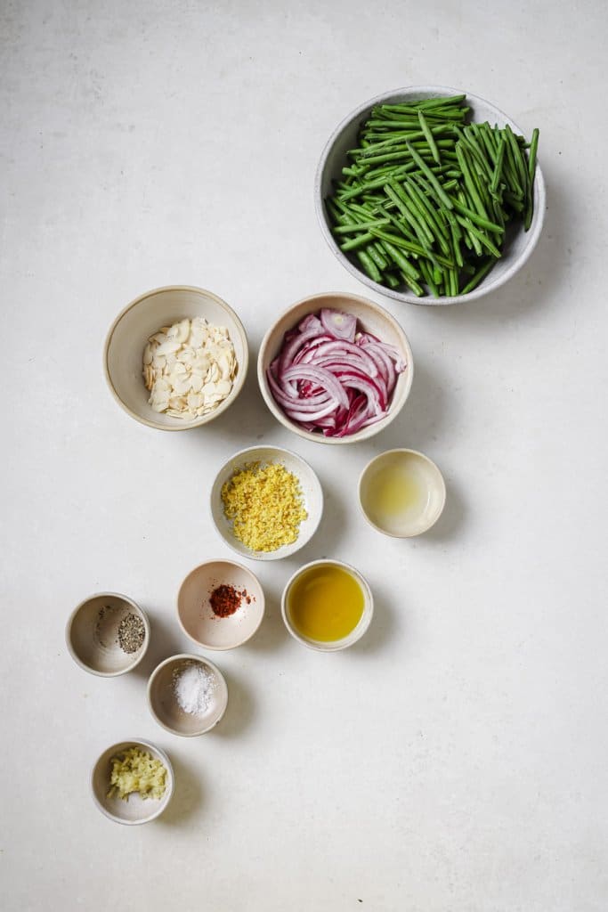 green beans, shallots, almonds, spices, garlic, and olive oil in small ingredient bowls