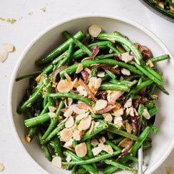 green beans almondine in a white serving bowl with a spoon