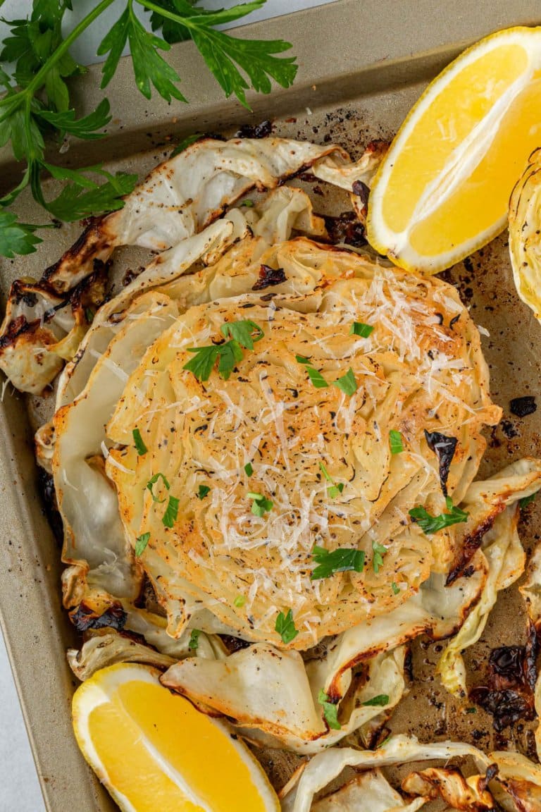 roasted cabbage steak on a sheet pan with lemon wedges and parsley