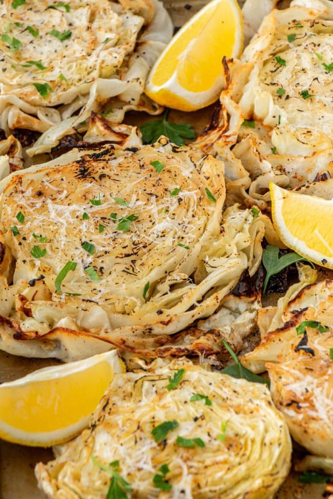 close up of roasted cabbage steaks with lemon wedges