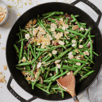 Green Beans Almondine in a black cast iron skillet with a wooden spoon