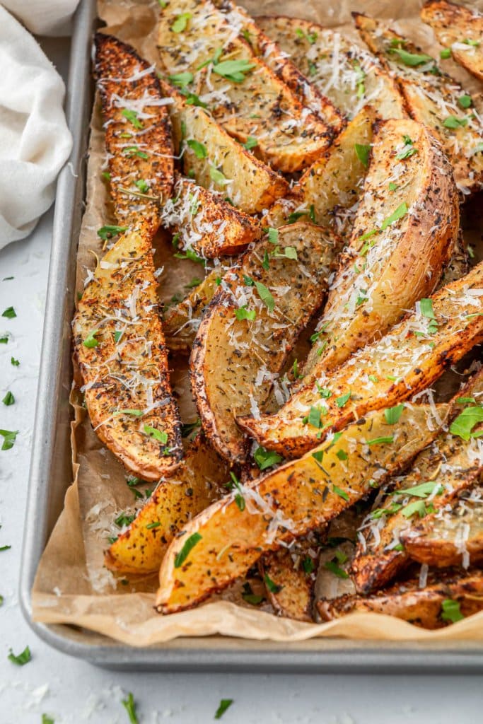 air fryer potato wedges on a baking tray topped with parmesan cheese and parsley