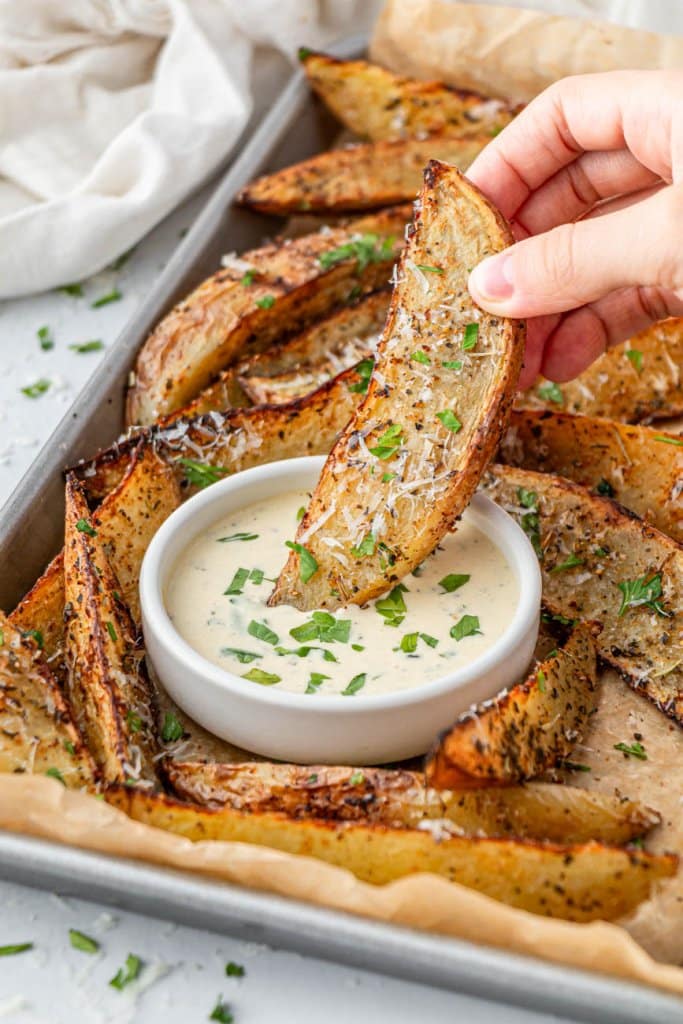 dipping a potato wedge in ranch dressing