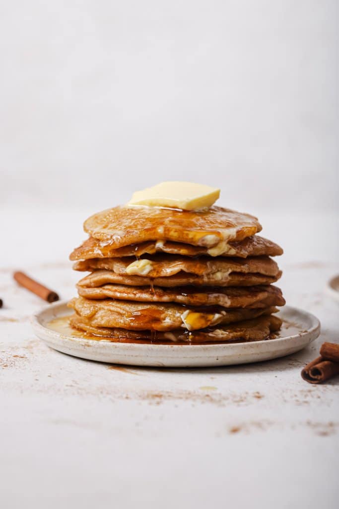 a stack of spiced apple pancakes on a plate with a square of butter melting on top