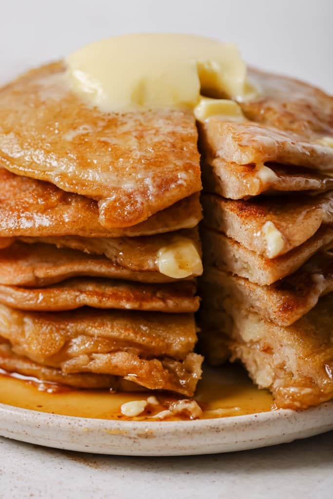 close up of a stack of pancakes sliced in half with butter on top