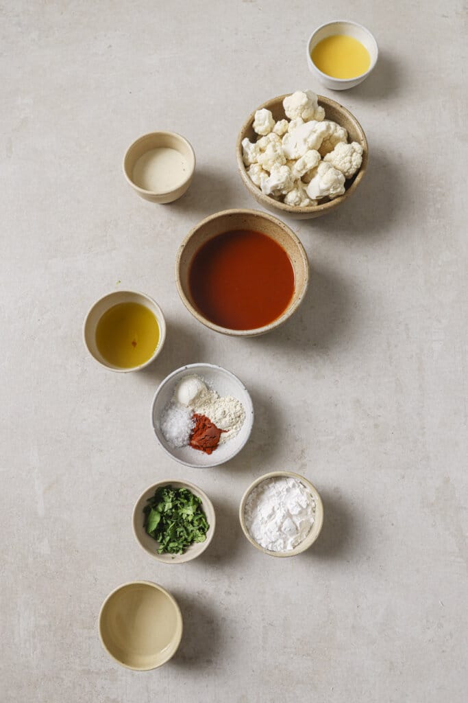 buffalo sauce, cauliflower, cilantro, and spices in small ingredient bowls