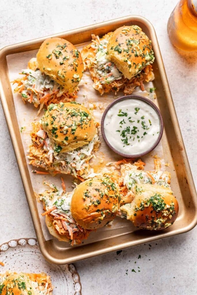 buffalo chicken sliders on a sheet pan with ranch