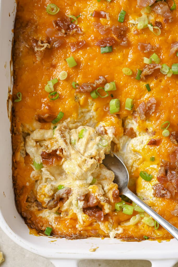 crack chicken dip in a white baking dish with a silver serving spoon