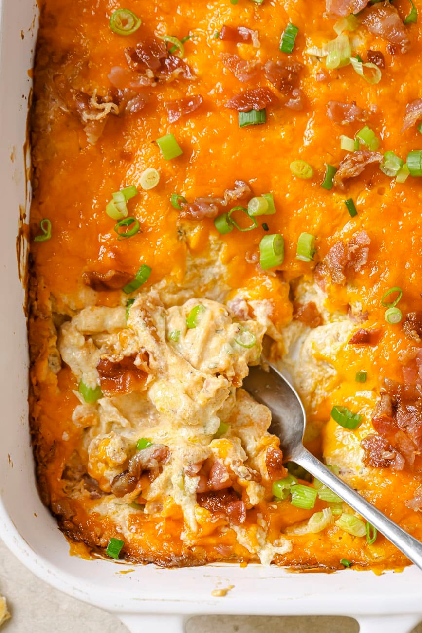 crack chicken dip in a white baking dish with a silver serving spoon