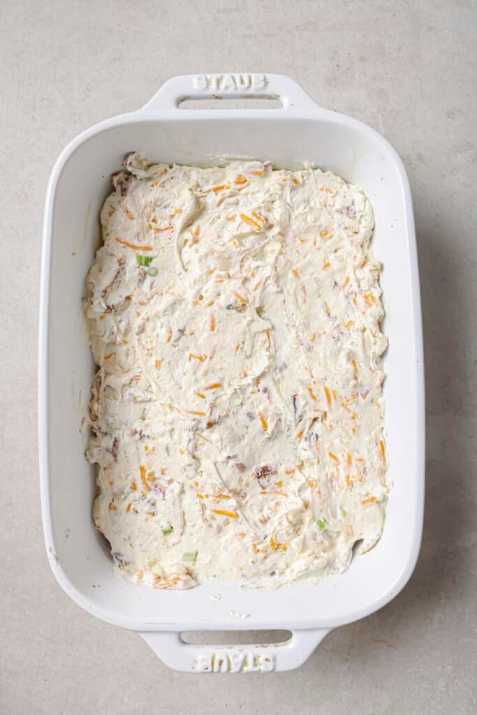 crack chicken dip in a white baking dish before baking.