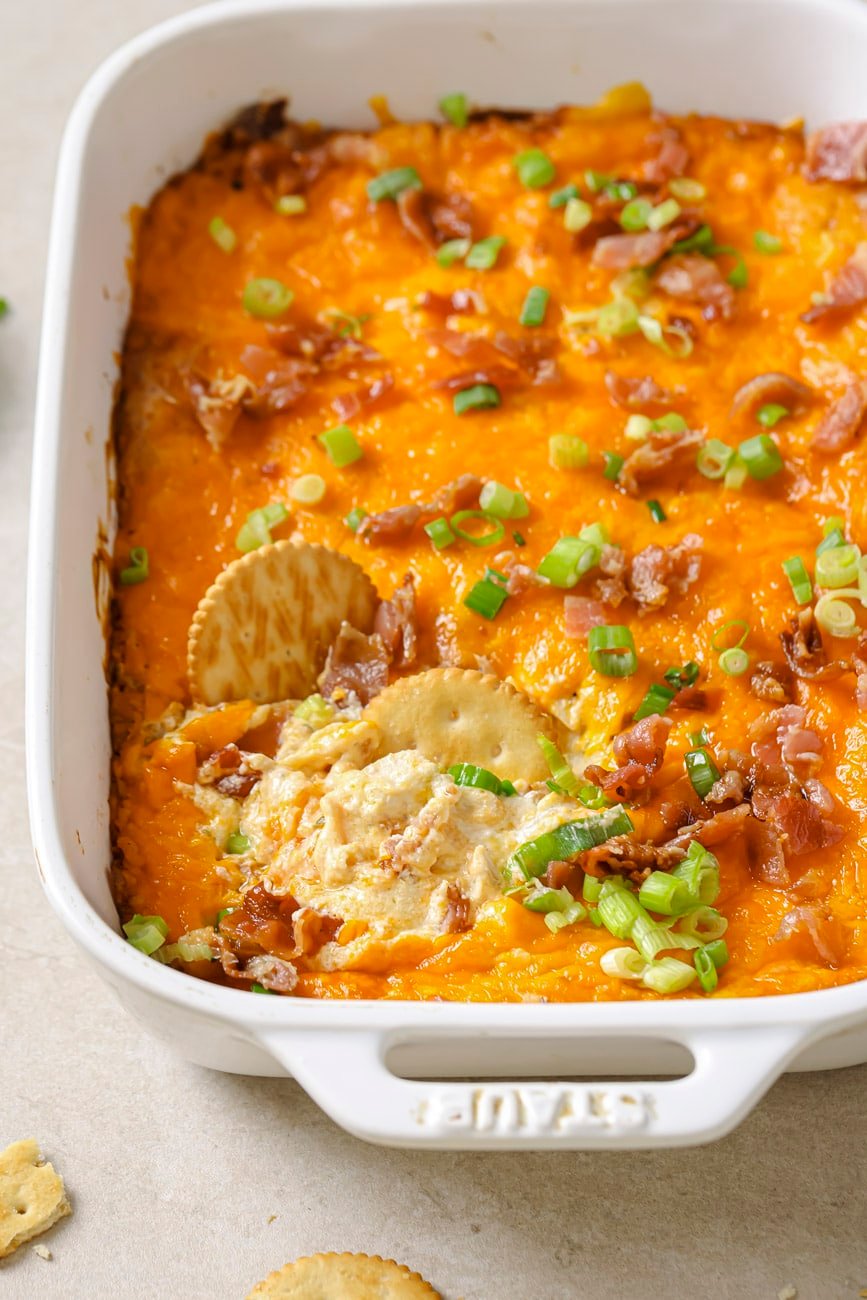 crack chicken dip in a white baking dish with two ritz crackers dipped inside