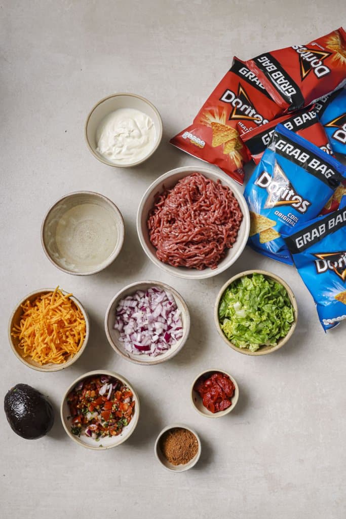 walking taco ingredients: ground beef, red onion, cheese, tomato paste, and doritos