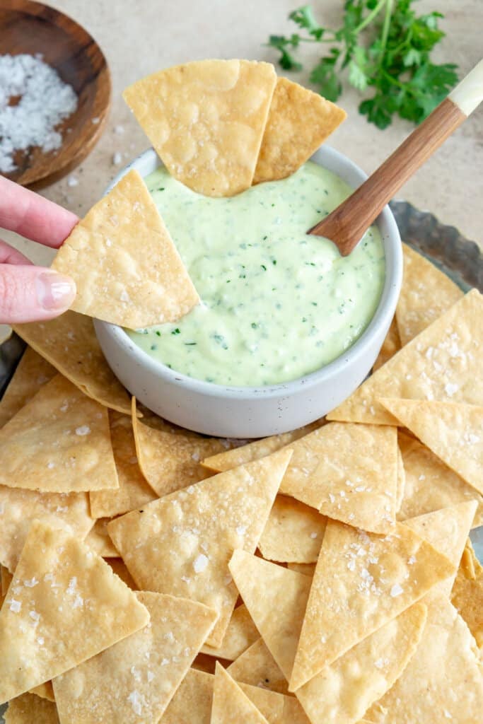 hand dipping a tortilla chip in jalapeño ranch dressing