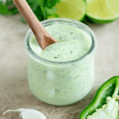 jalapeno ranch dressing in a glass jar with a wood spoon