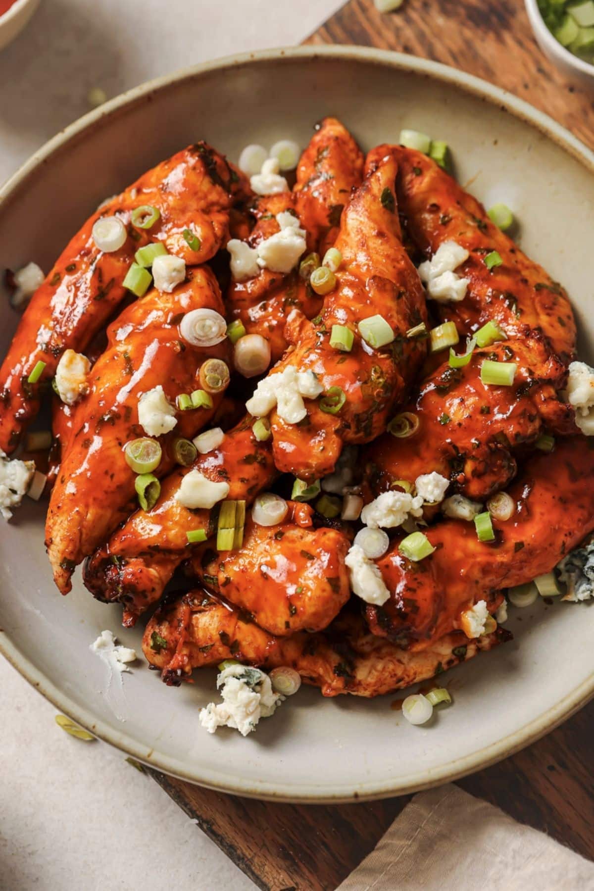 A ceramic plate full of buffalo chicken tenders topped with blue cheese crumbles.