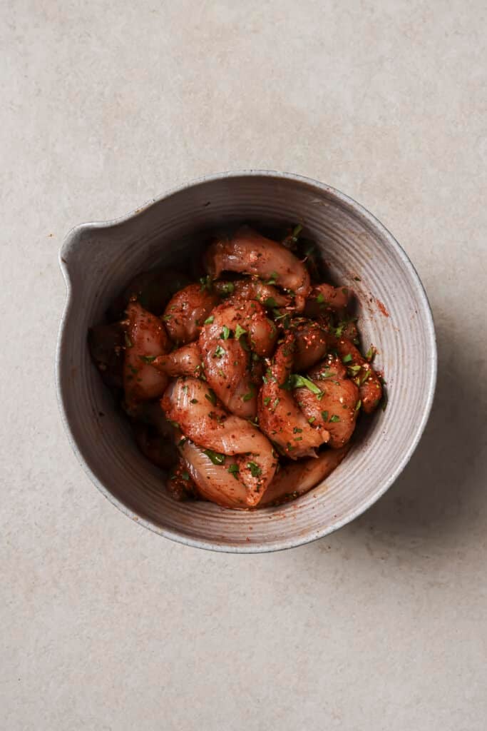 Chicken tenders in a bowl tossed with seasoning mix.