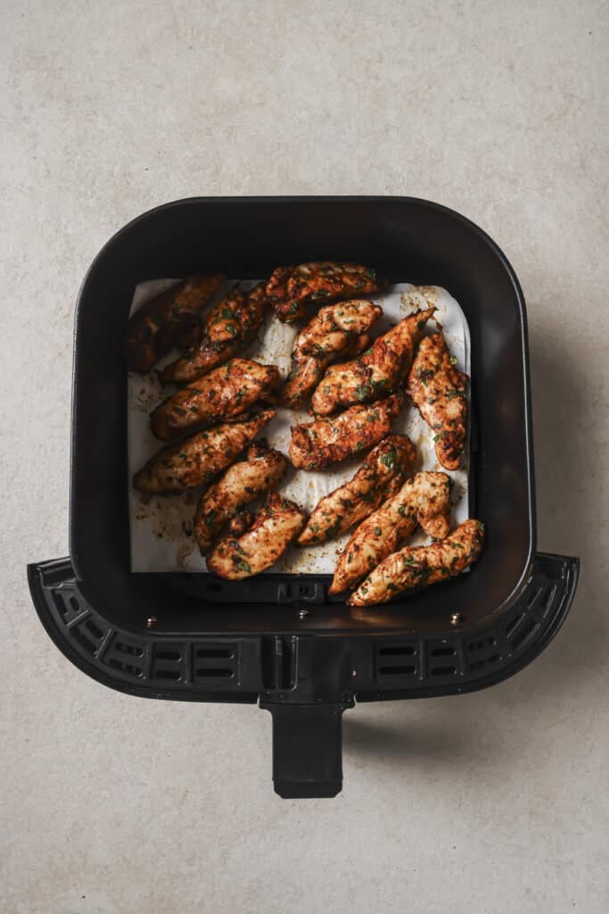 Seasoned chicken tenders in an air fryer.