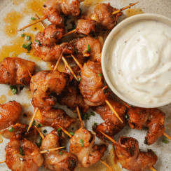 air fryer bacon wrapped shrimp on a plate with a small bowl of garlic aioli