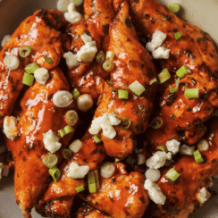 air fryer buffalo chicken tenders on a plate with crumbled blue cheese and green onion