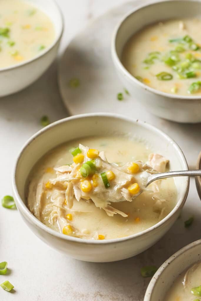 chicken corn soup in a bowl with a spoon taking a bite out