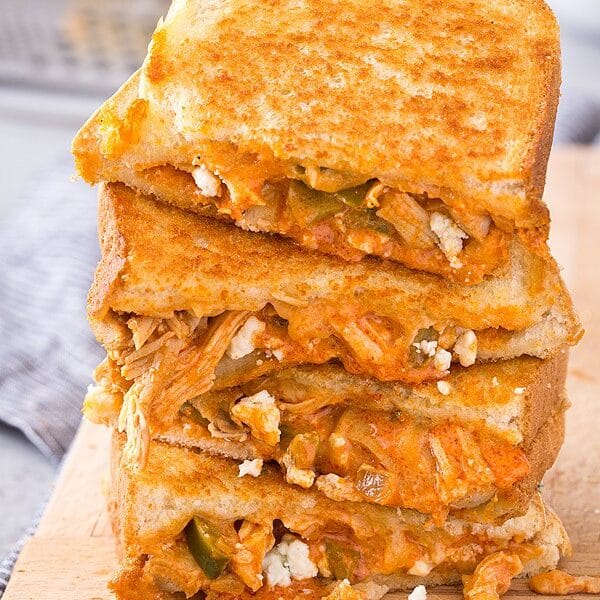 Side view of four halves of buffalo chicken grilled cheese sandwiches stacked on top of each other.