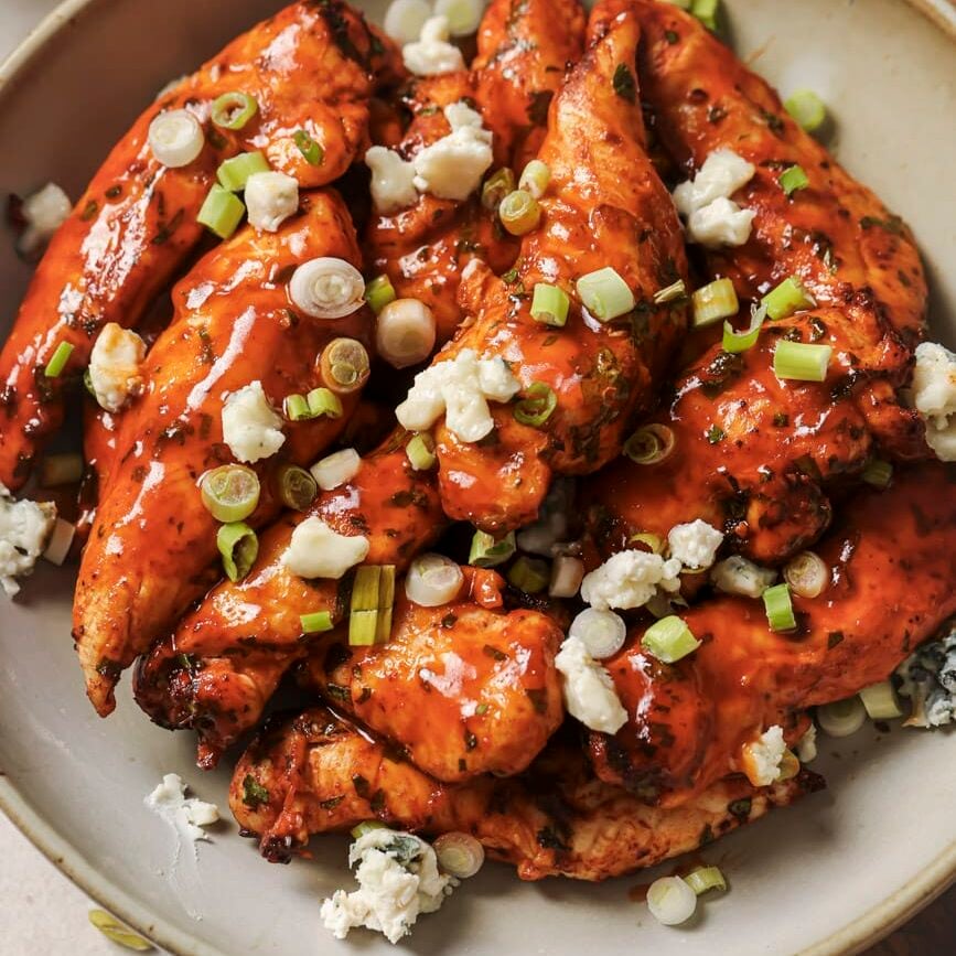air fryer buffalo chicken tenders on a plate with blue cheese crumbles and green onion