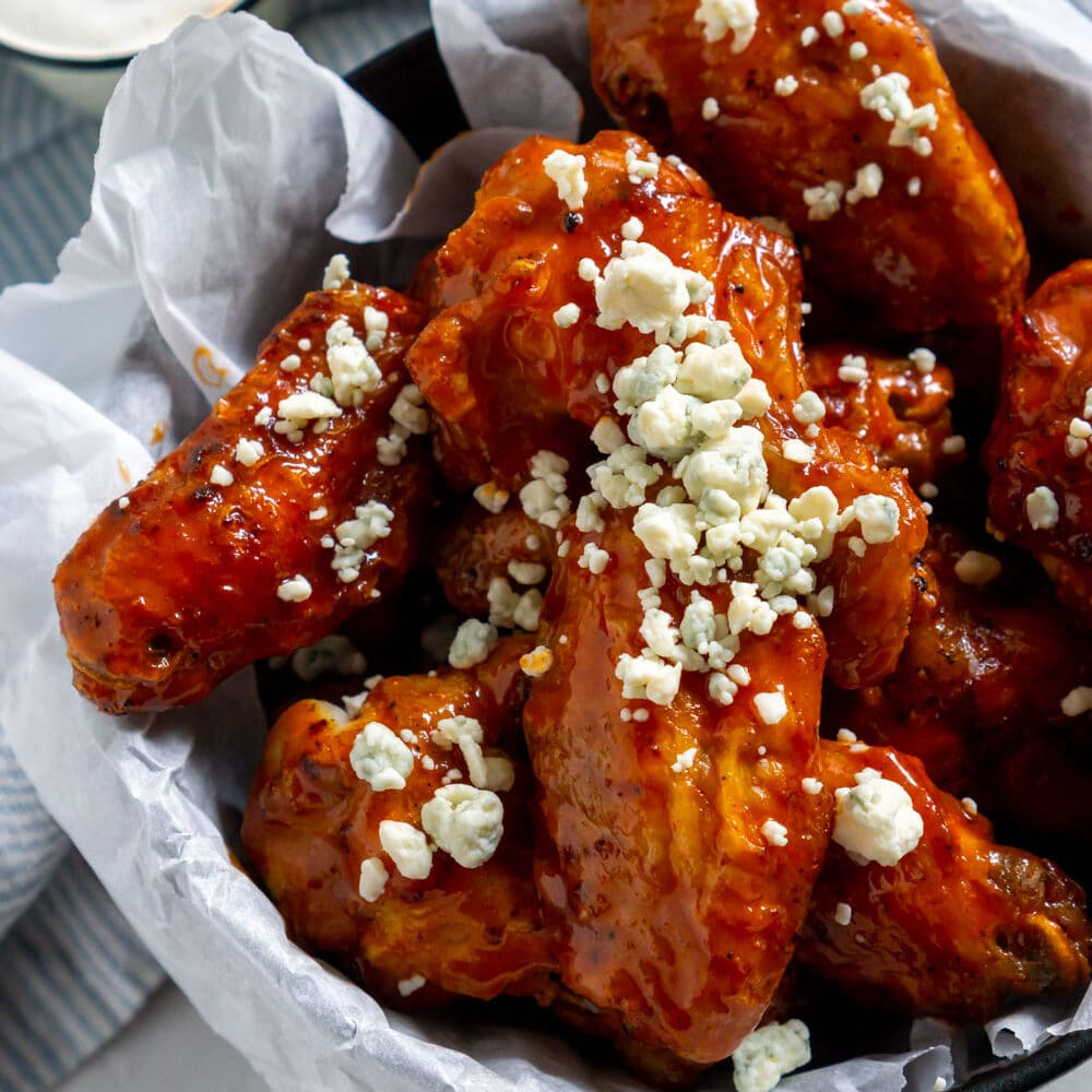 air fryer buffalo wings in a bowl with blue cheese crumbles