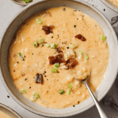 roasted corn chowder in a bowl topped with bacon and green onions with a spoon
