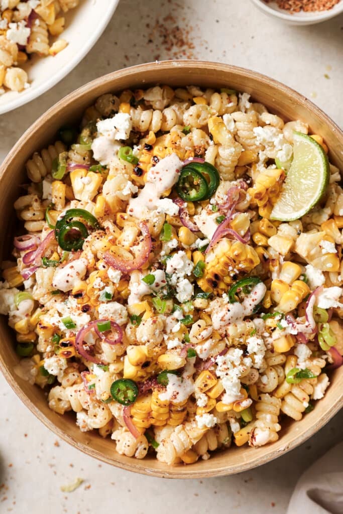 mexican street corn pasta salad in a bowl with a lime wedge