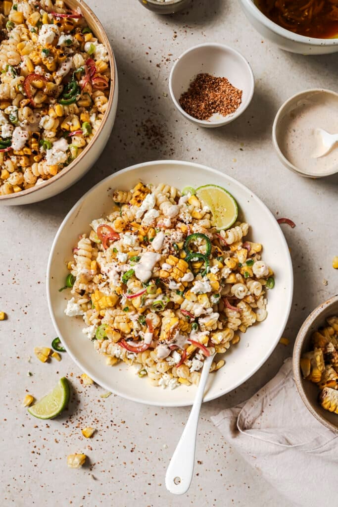 mexican street corn pasta salad in a bowl with a lime wedge