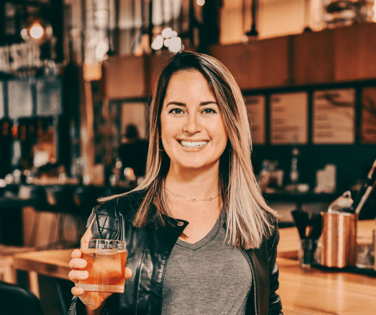 a girl wearing a black leather jacket holding a drink