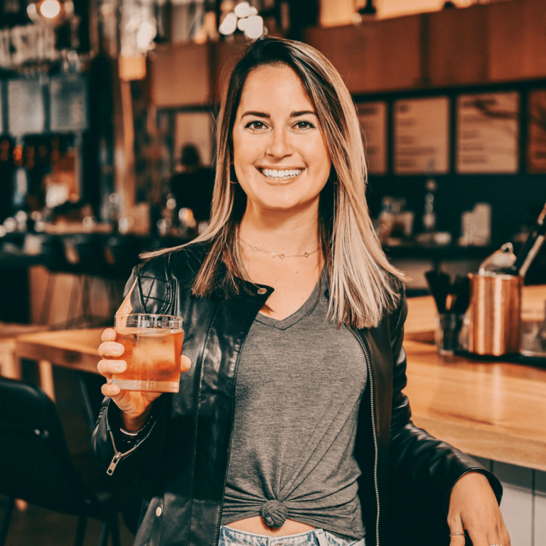 a girl wearing a black leather jacket holding a drink