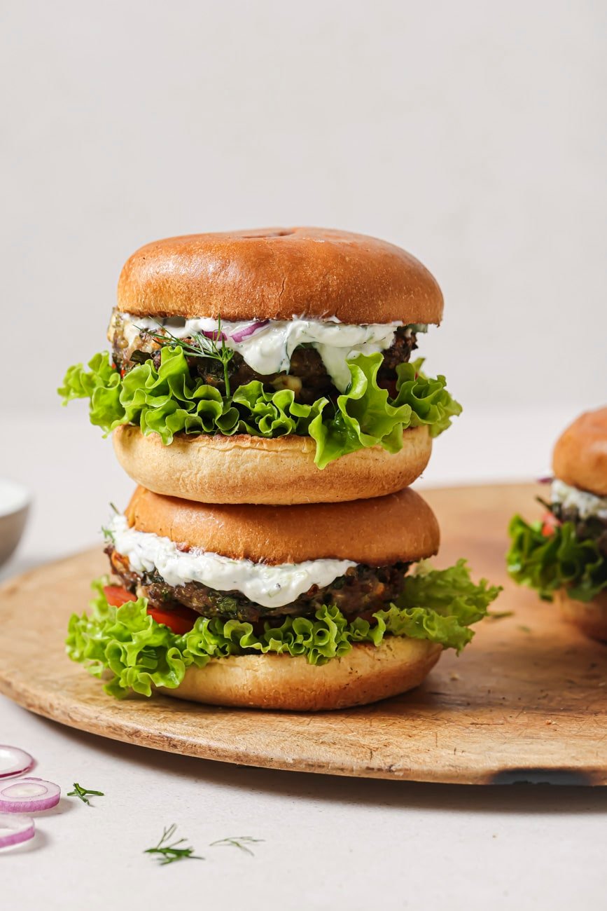 Side view of two air fryer turkey burgers stacked on a wooden cutting board.