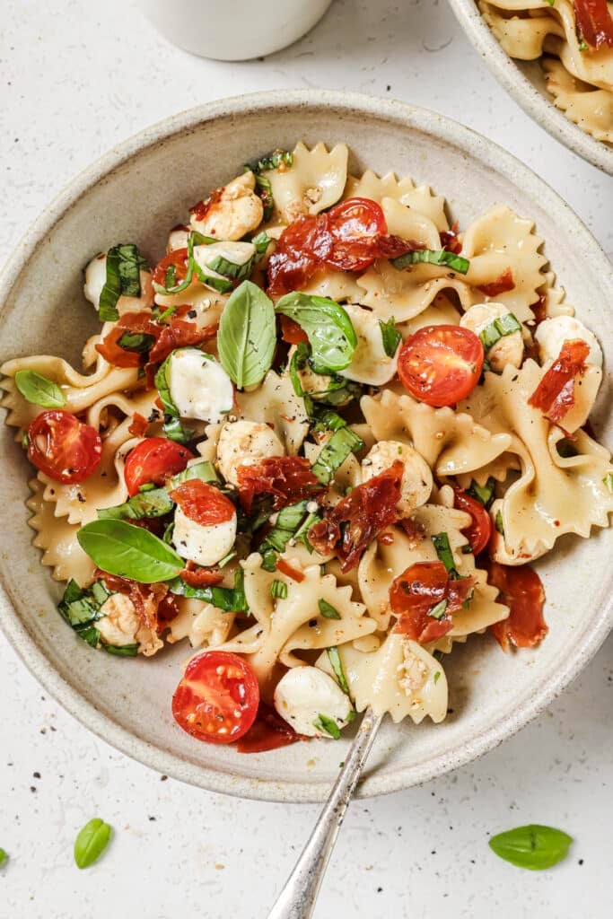 Caprese pasta salad in a bowl with a fork.