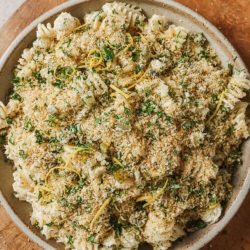 Dill Pickle Pasta Salad in a white bowl on a wood board