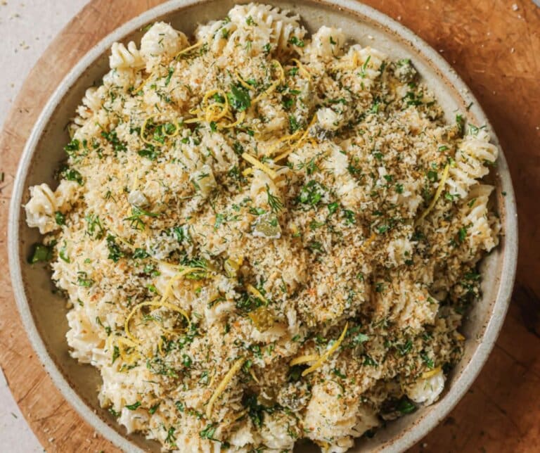 Dill Pickle Pasta Salad in a white bowl on a wood board