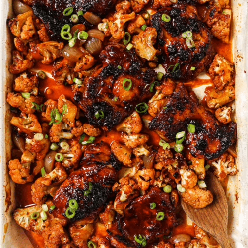 gochujang chicken thighs on a sheet pan with a wooden spoon