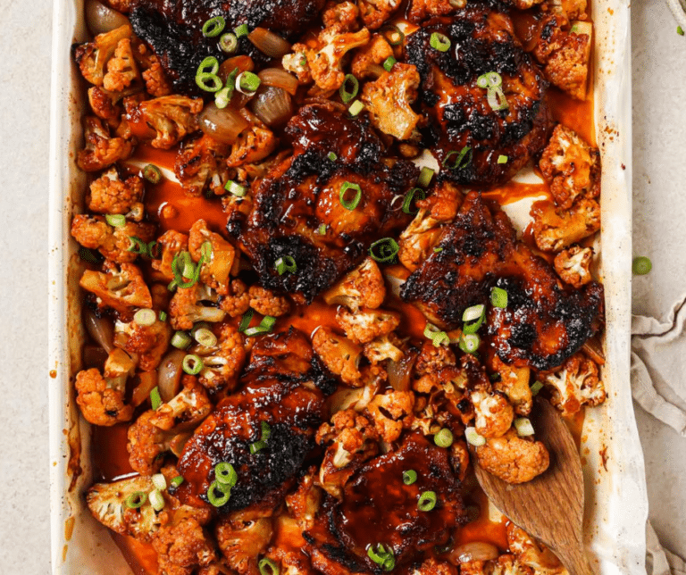 gochujang chicken thighs on a sheet pan with a wooden spoon