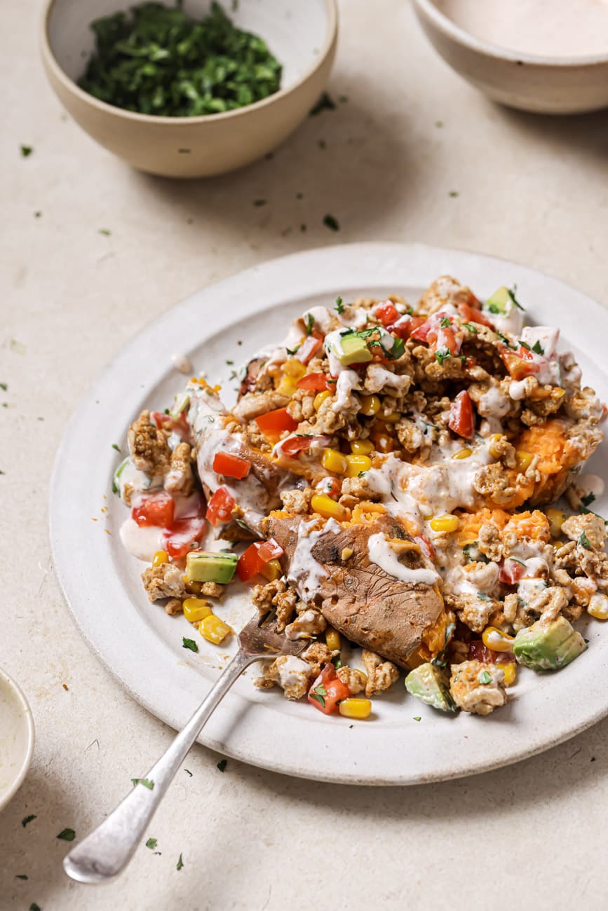 A plate of taco stuffed sweet potatoes with toppings and chili lime crema.