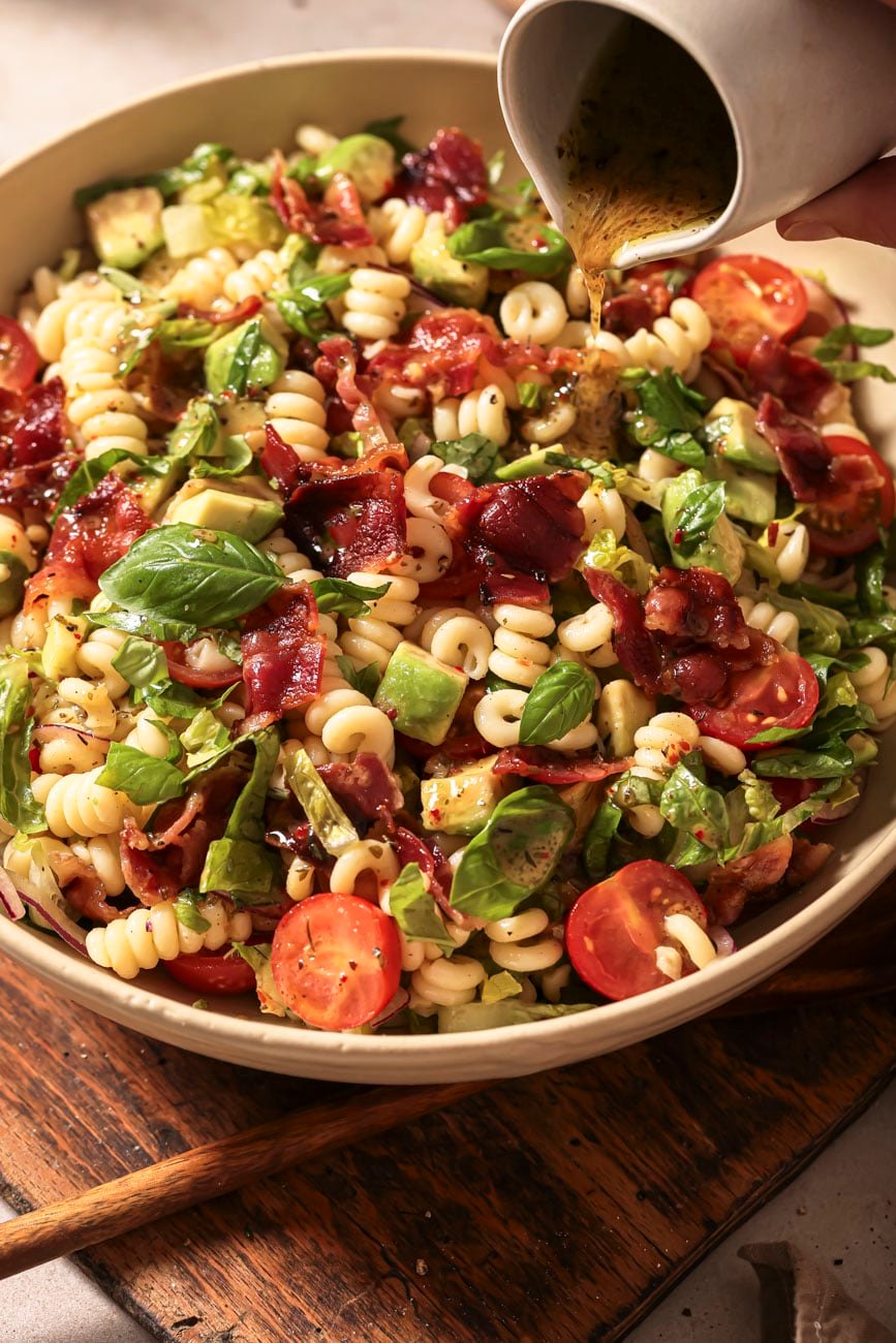 Close up of dressing pouring over BLT salad.