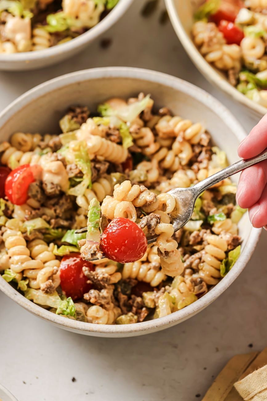 Lifting up a forkful of cheeseburger pasta salad from a bowl.